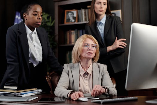 Business professionals in a team meeting around a computer discussing work strategies.