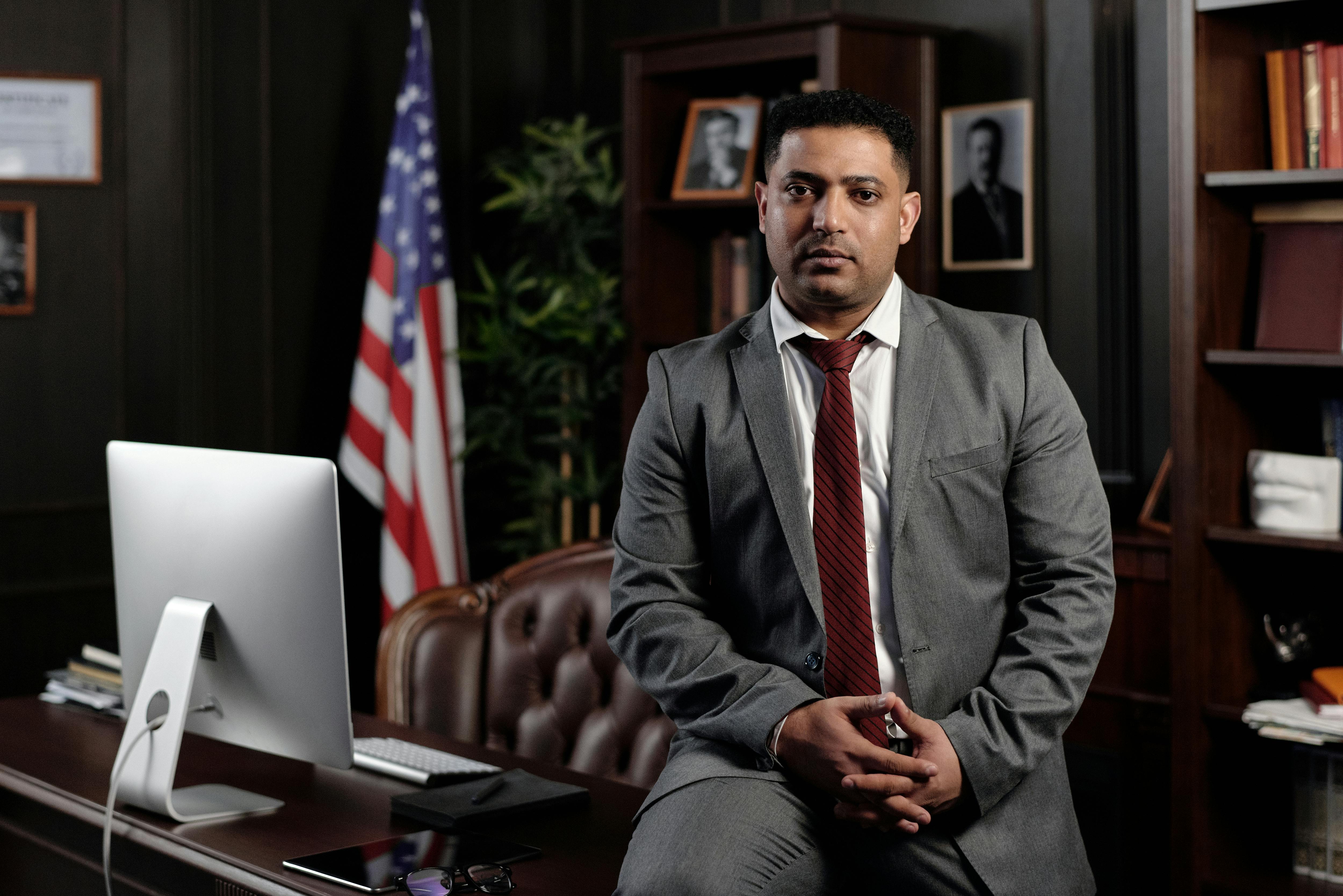 businessman sitting on his desk and looking at the camera