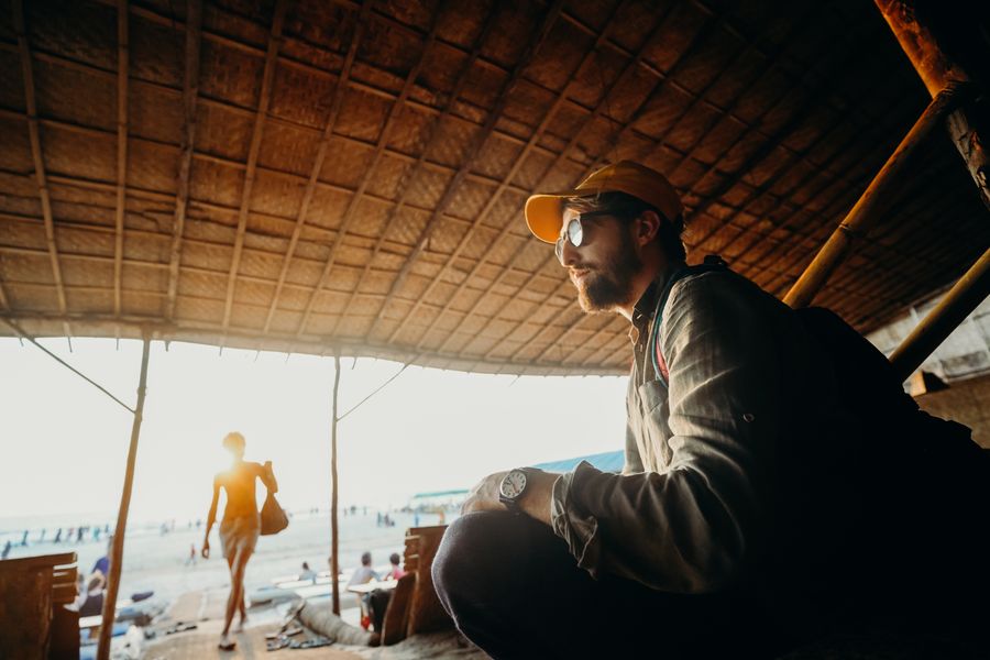 Man under a sunshade at the beach enjoying summer vibes in Goa, India.