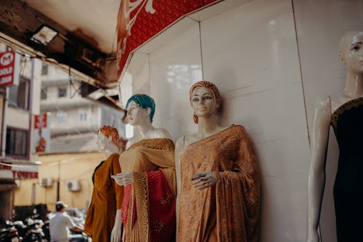 Mannequins showcasing traditional sarees in an Indian bazaar setting with vibrant fabrics.