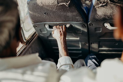 Person in White Long Sleeve Shirt Holding Black Car Steering Wheel