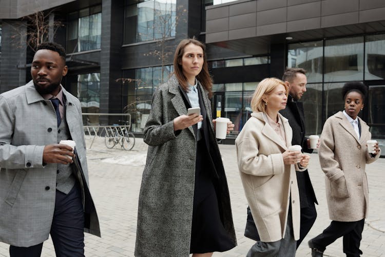 Coworkers Taking A Coffee Break And Walking