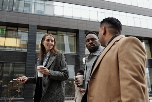 Free A group of diverse professionals discussing business during a coffee break outdoors. Stock Photo