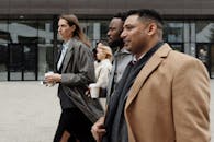 一群多元化的商业专业人士拿着咖啡杯，在外面边走边讨论工作