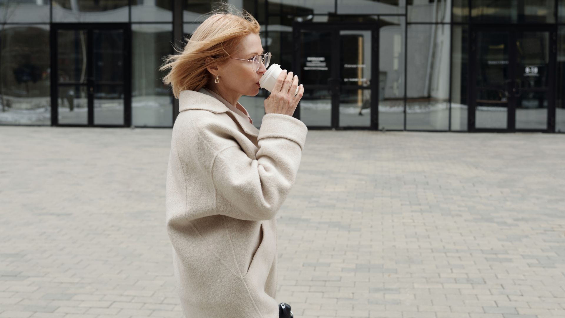 Woman Drinking from a Disposable Cup While Walking