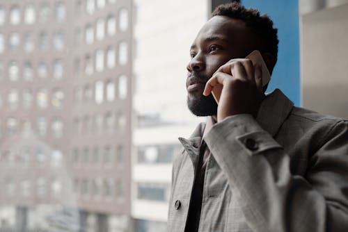 Man in Gray Button Up Coat Using a Smartphone