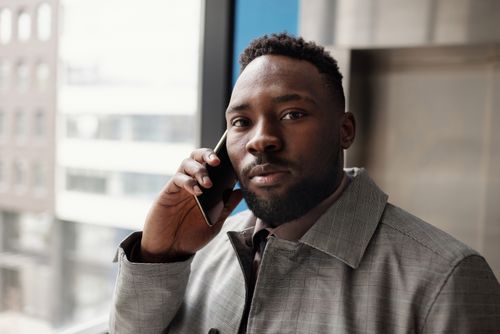 Free A professional man in a suit making a phone call indoors, conveying business confidence. Stock Photo
