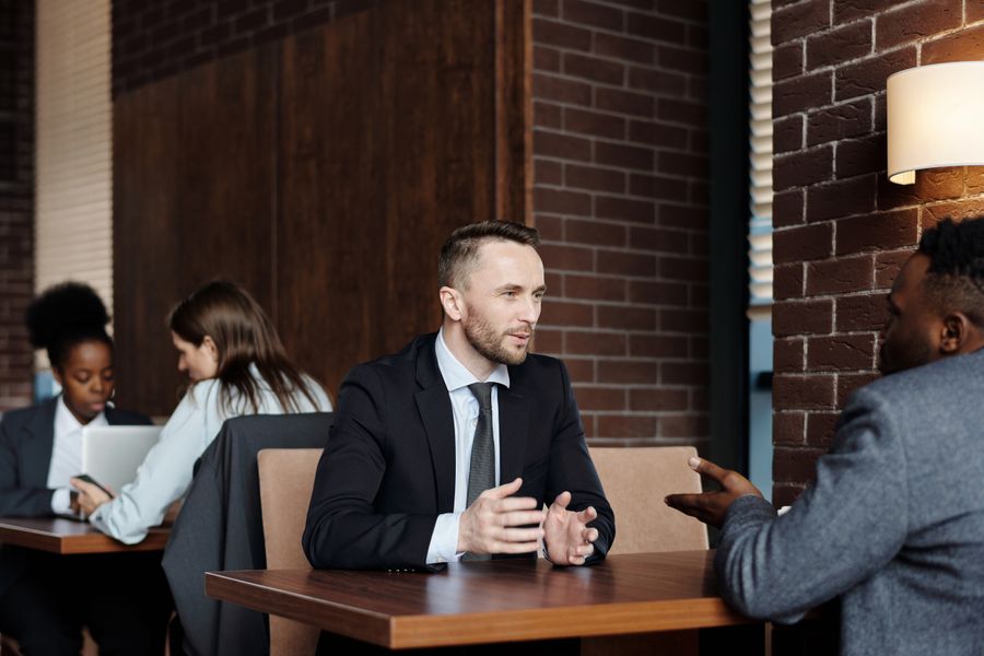 Businessmen engaged in a professional conversation in a stylish café setting.