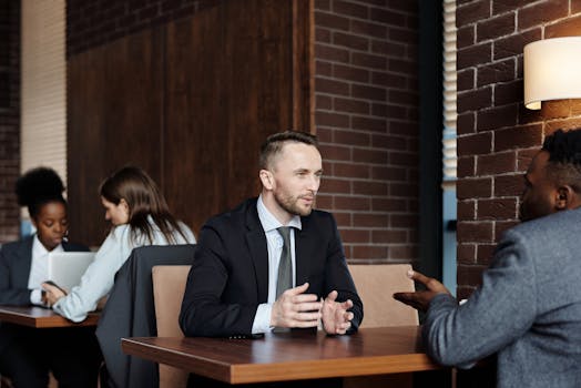 Businessmen engaged in a professional conversation in a stylish café setting.