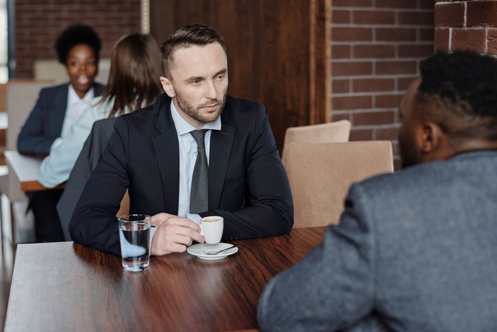Two businessmen discussing over coffee during a meeting