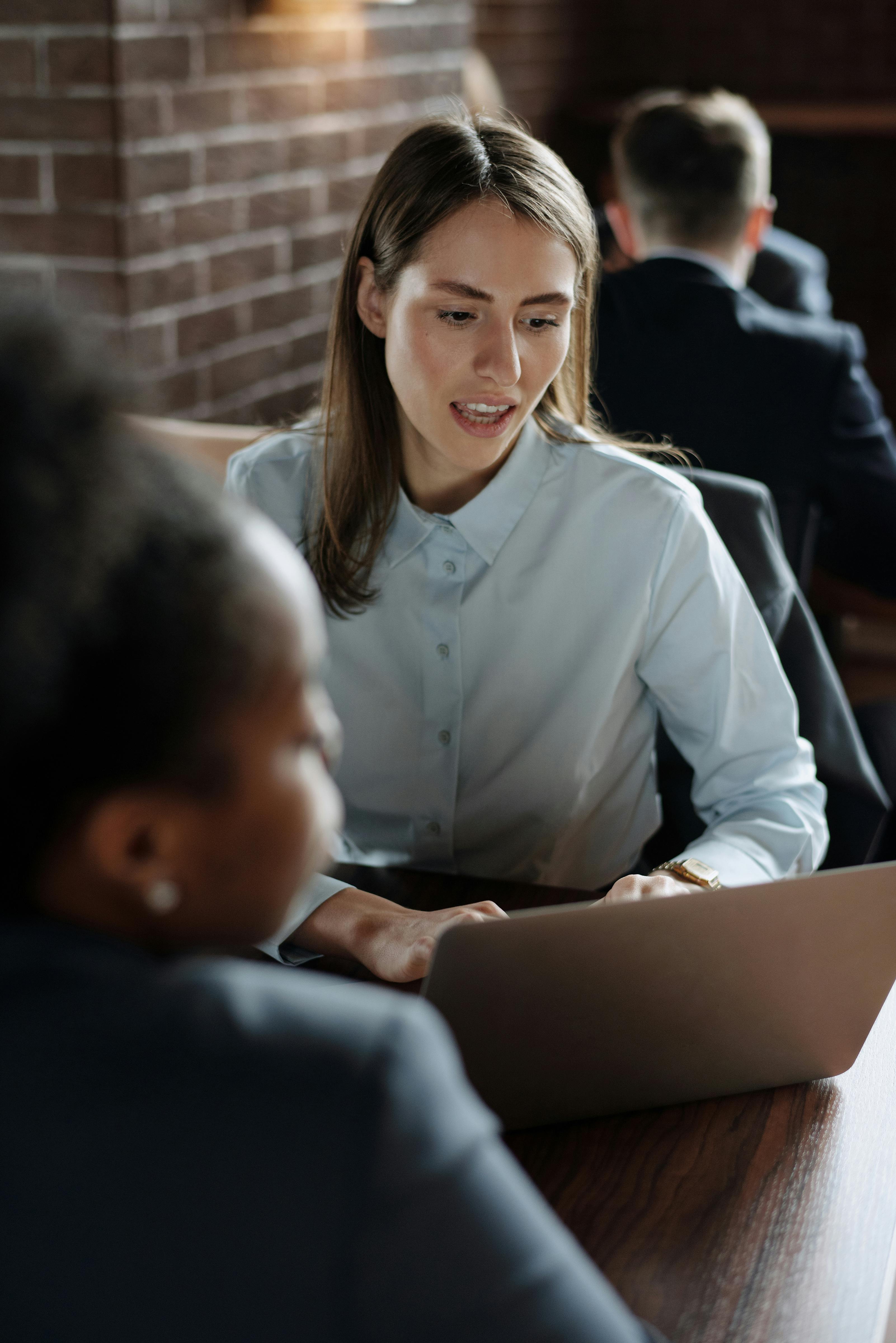 业务团队在室内围着一张放有笔记本电脑的木桌讨论策略