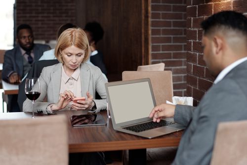 Free Business professionals engaging at a cafe with technology and wine, showcasing modern work culture. Stock Photo