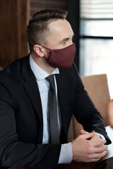 一名身穿西装、戴着口罩的商人在办公室举行正式会议，环境专业且现代