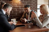 不同的业务团队在咖啡馆边品葡萄酒边用智能手机讨论