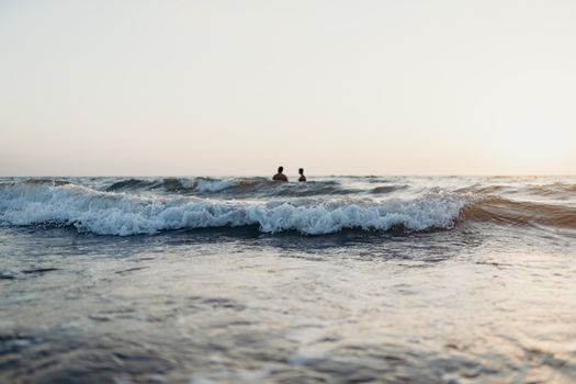 夕阳下，两人在海浪的宁静景色中游泳，非常适合夏季氛围