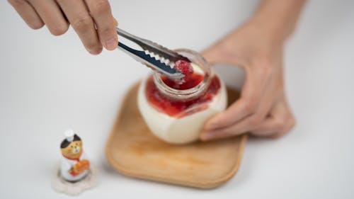 Crop person decorating yogurt with berries