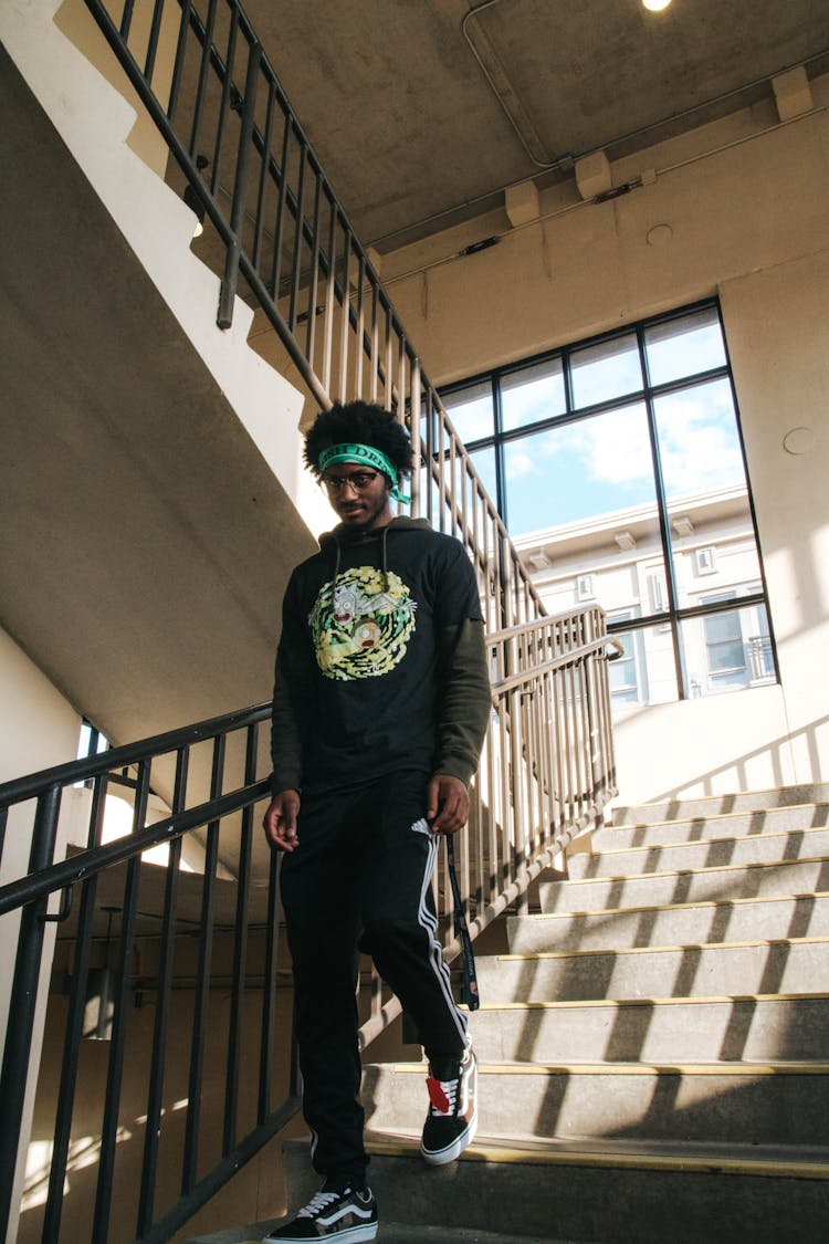 Young Black Man Going Downstairs In Building Hall