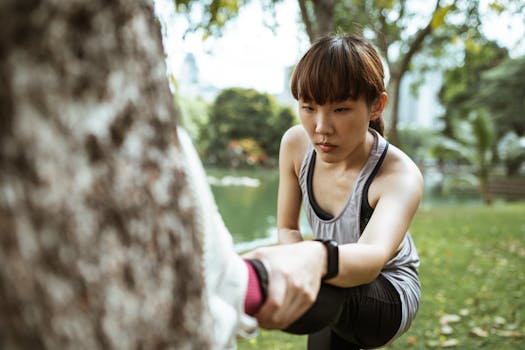 Focused young woman in activewear stretching in a city park, emphasizing fitness and wellbeing.