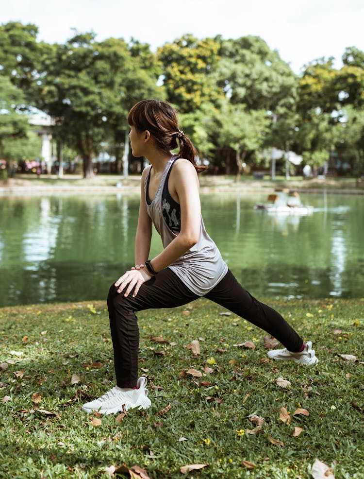 Slim Asian Woman Exercising On Pond Shore