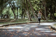 阳光明媚的日子里，一名年轻女子在绿树成荫的公园里慢跑