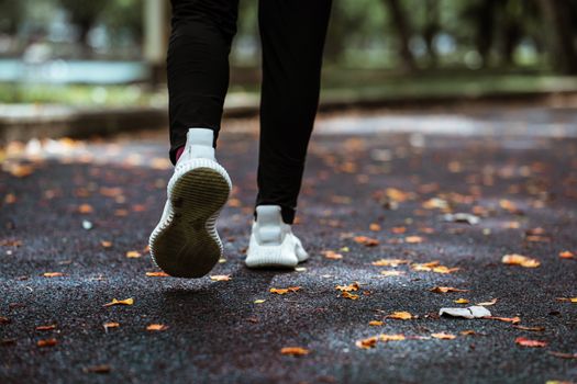 人行道上，一双穿着白色运动鞋和黑色紧身裤的腿在奔跑