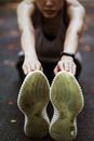 Anonymous flexible female in sportswear and sneakers warming up before exercising on sports ground