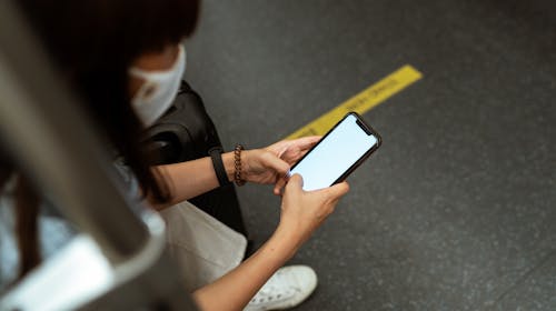 Woman Wearing a Face Mask and Holding a Smartphone