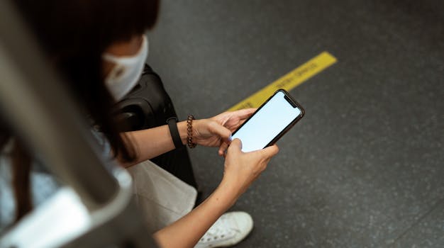 A commuter wearing a face mask uses a smartphone on public transit, reflecting pandemic lifestyle.