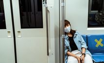 地铁上，一名戴口罩的女子正在休息，捕捉到了疫情期间城市旅行的本质