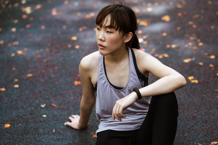 Fit Asian Woman In Sportswear Sitting On Pavement In Fall