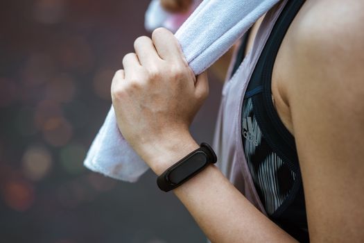 Side view of crop faceless female athlete in black smart watch and sports clothes holding cotton towel after practicing sport outdoors