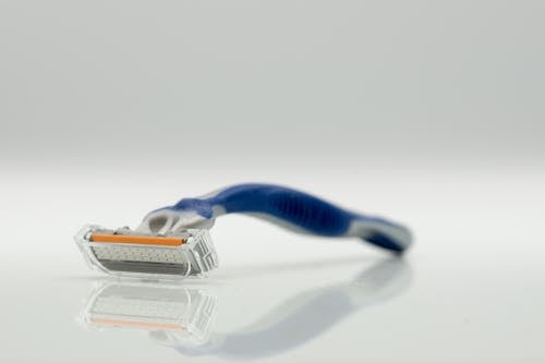 Close-Up Photo of a Blue and Gray Razor on a White Surface