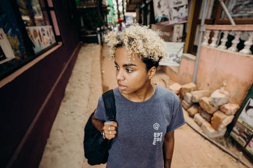 Boy in Blue Crew Neck T-shirt Standing Near Brown Concrete Building