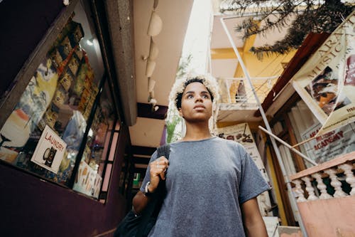 Woman in Gray Crew Neck T-shirt Standing Near Brown Wooden Shelf