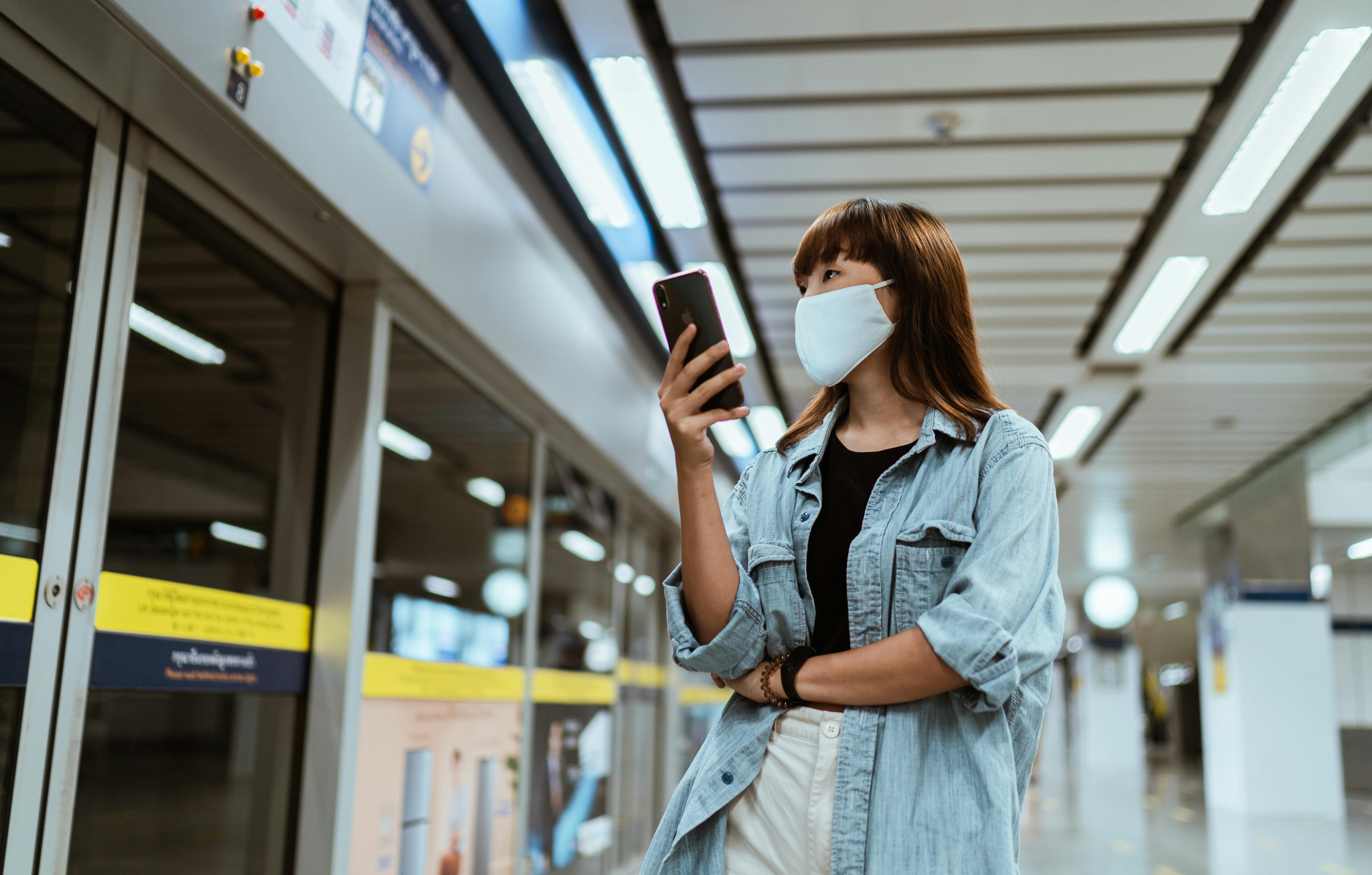 woman wearing a face mask and holding a smartphone