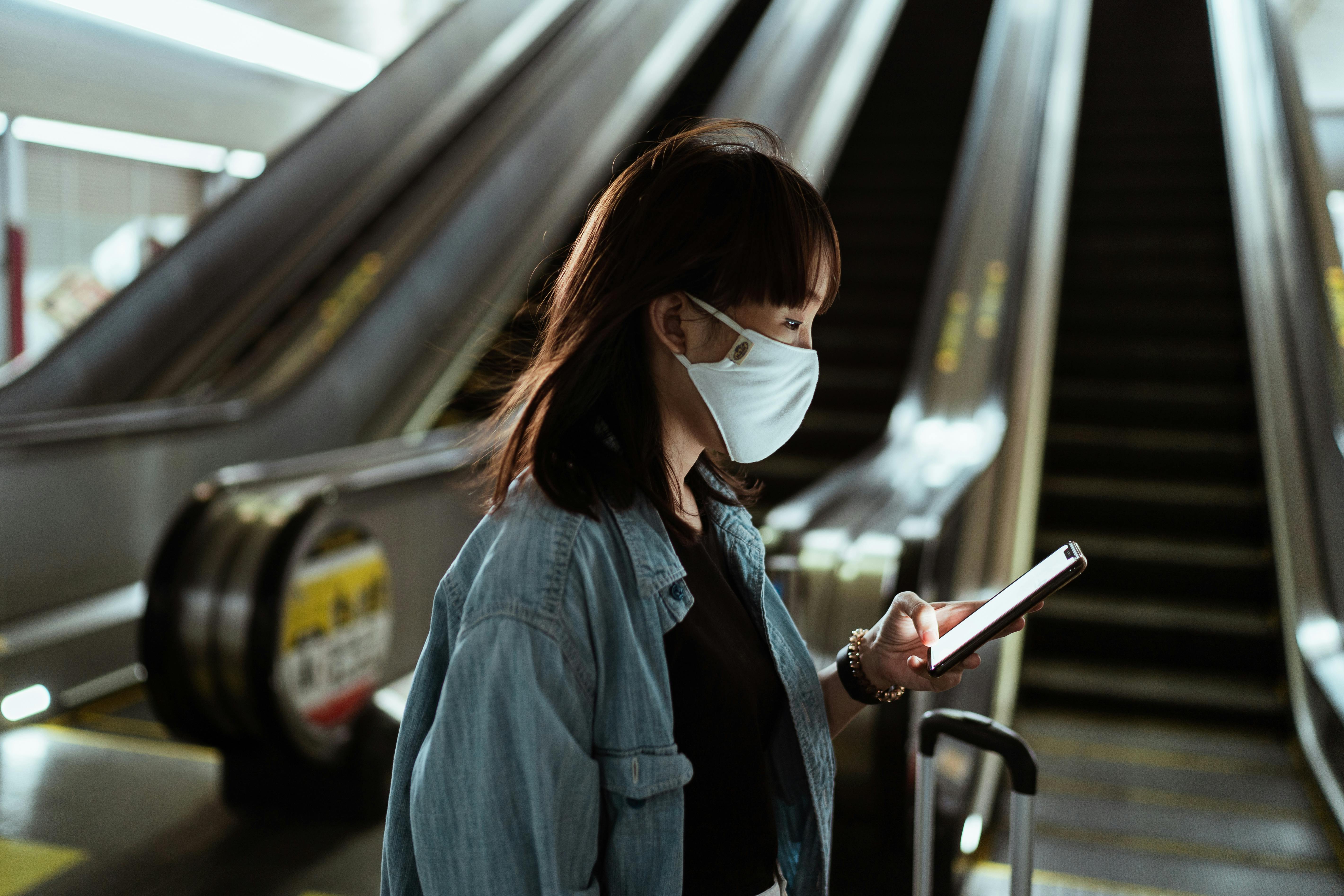 woman wearing a face mask and holding a smartphone