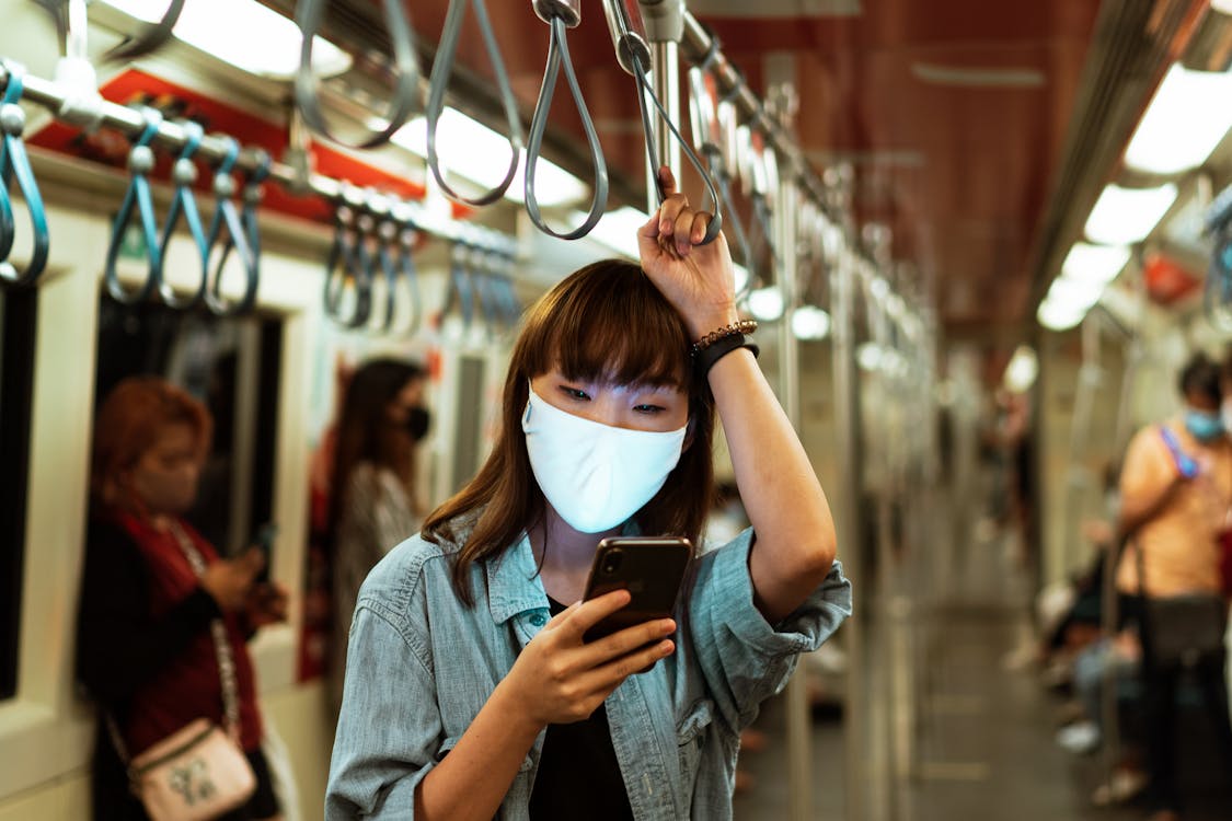 Free Woman Wearing a Face Mask on the Subway and Using her Smartphone Stock Photo