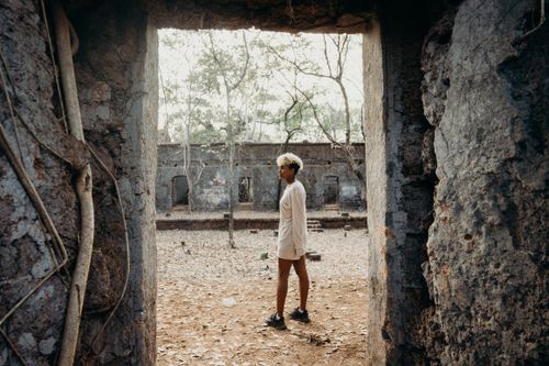 Free A young woman with curly hair explores ancient ruins in a jungle setting. Stock Photo