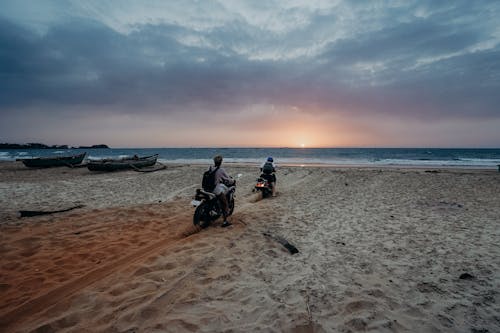 Man in Black Jacket Sitting on Black Motorcycle on Beach