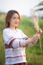 在阳光明媚的夏日户外，一位微笑的女人抱着草坐在草地上