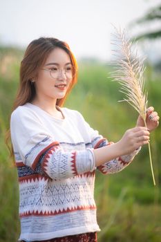在阳光明媚的夏日户外，一位微笑的女人抱着草坐在草地上