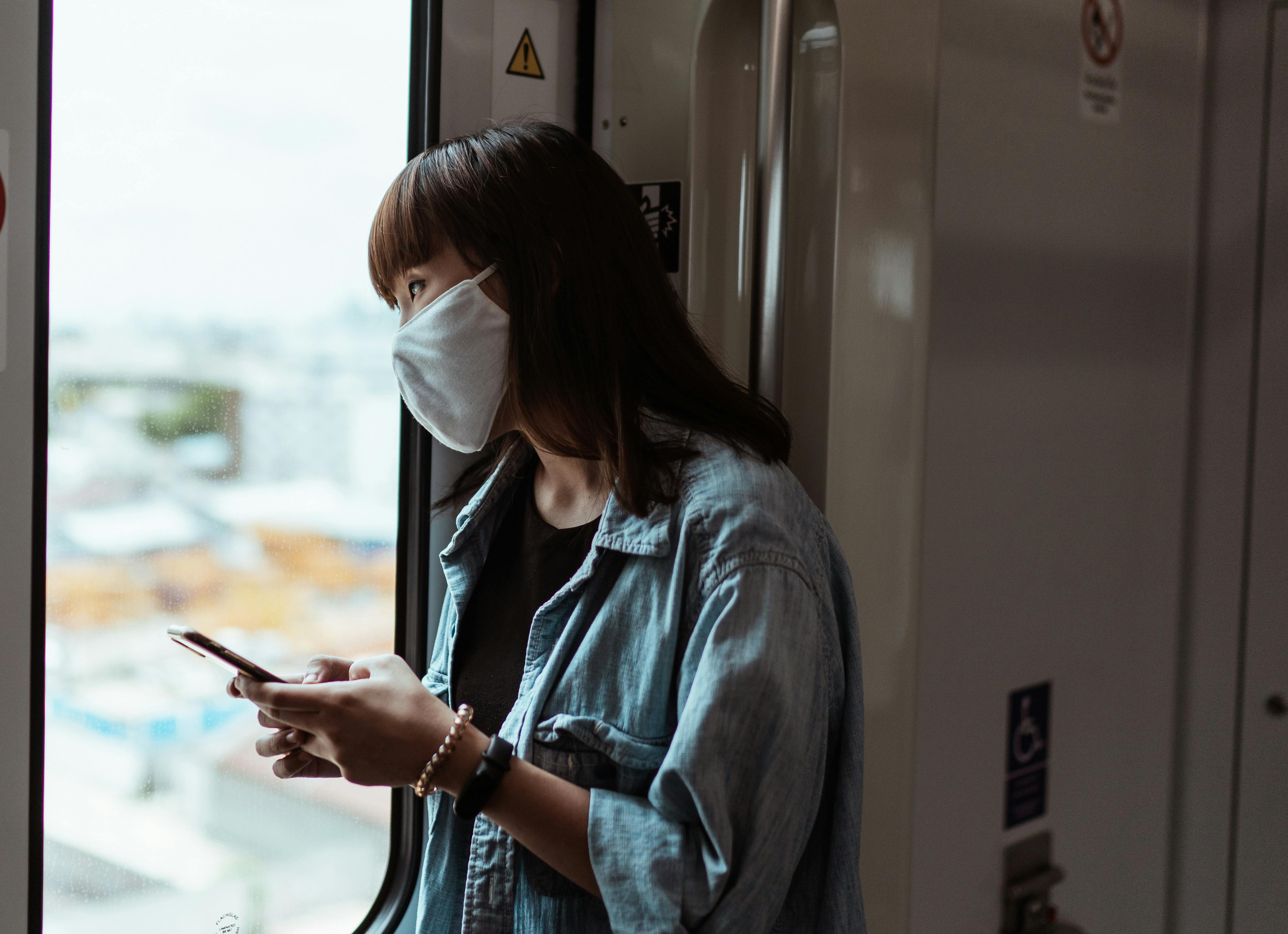 woman wearing a face mask and holding a smartphone
