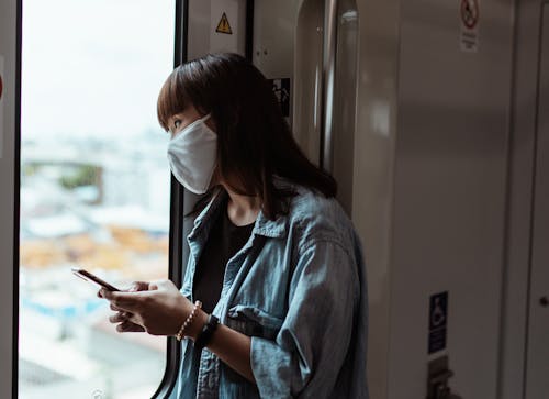 Woman Wearing a Face Mask and Holding a Smartphone