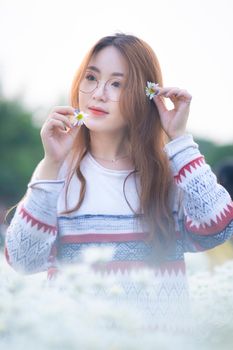 一位年轻的亚洲女性身着休闲服，戴着眼镜，站在开满洋地黄花的春日花园里，目光望向别处