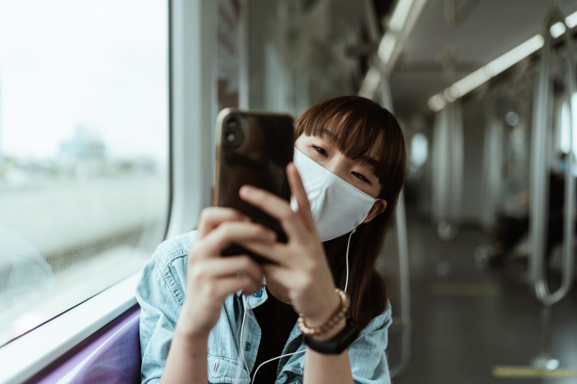 Mulher Usando Uma Máscara Facial E Segurando Um Smartphone
