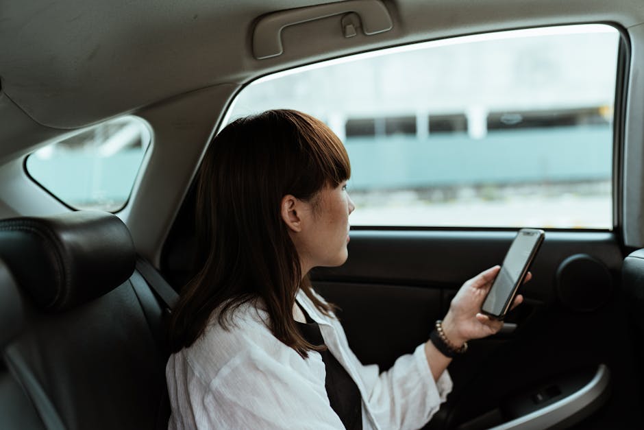 Calm woman browsing smartphone in car backseat