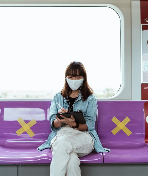 Free Asian woman in face mask using tablet on subway, practicing social distancing. Stock Photo