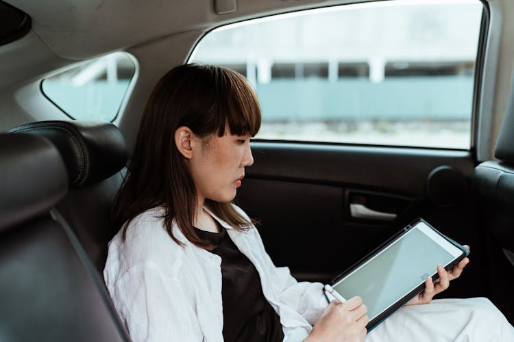 Focused Woman Working On Tablet In Car