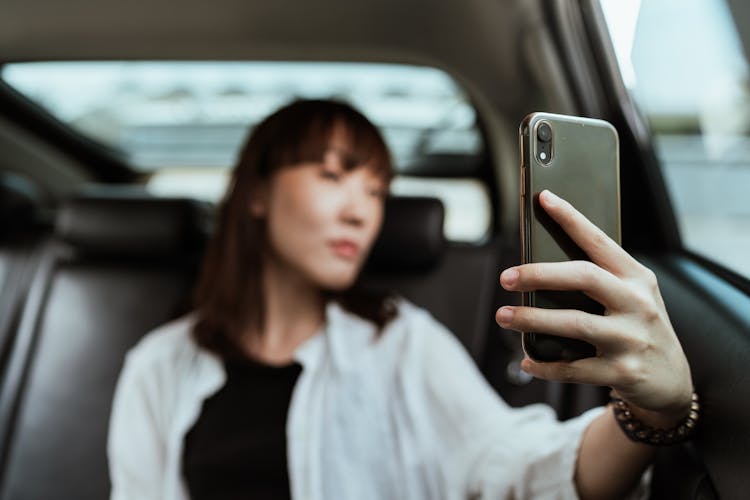 Calm Woman Taking Selfie On Smartphone In Car