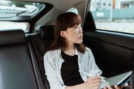 一名年轻女子坐在车里，手持触控笔，正全神贯注地盯着平板电脑